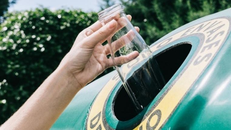 Botella de vidrio en el contenedor verde