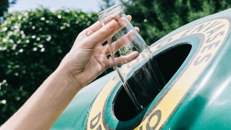 Botella de vidrio en el contenedor verde