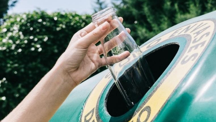 Botella de vidrio en el contenedor verde